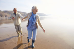 Senior Couple Running Along Winter Beach